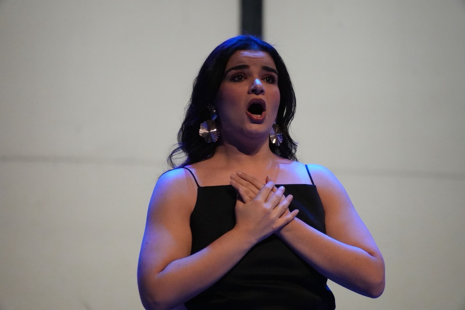 Stefany Cruz-Chousal interpretando un aria con las manos sobre el pecho