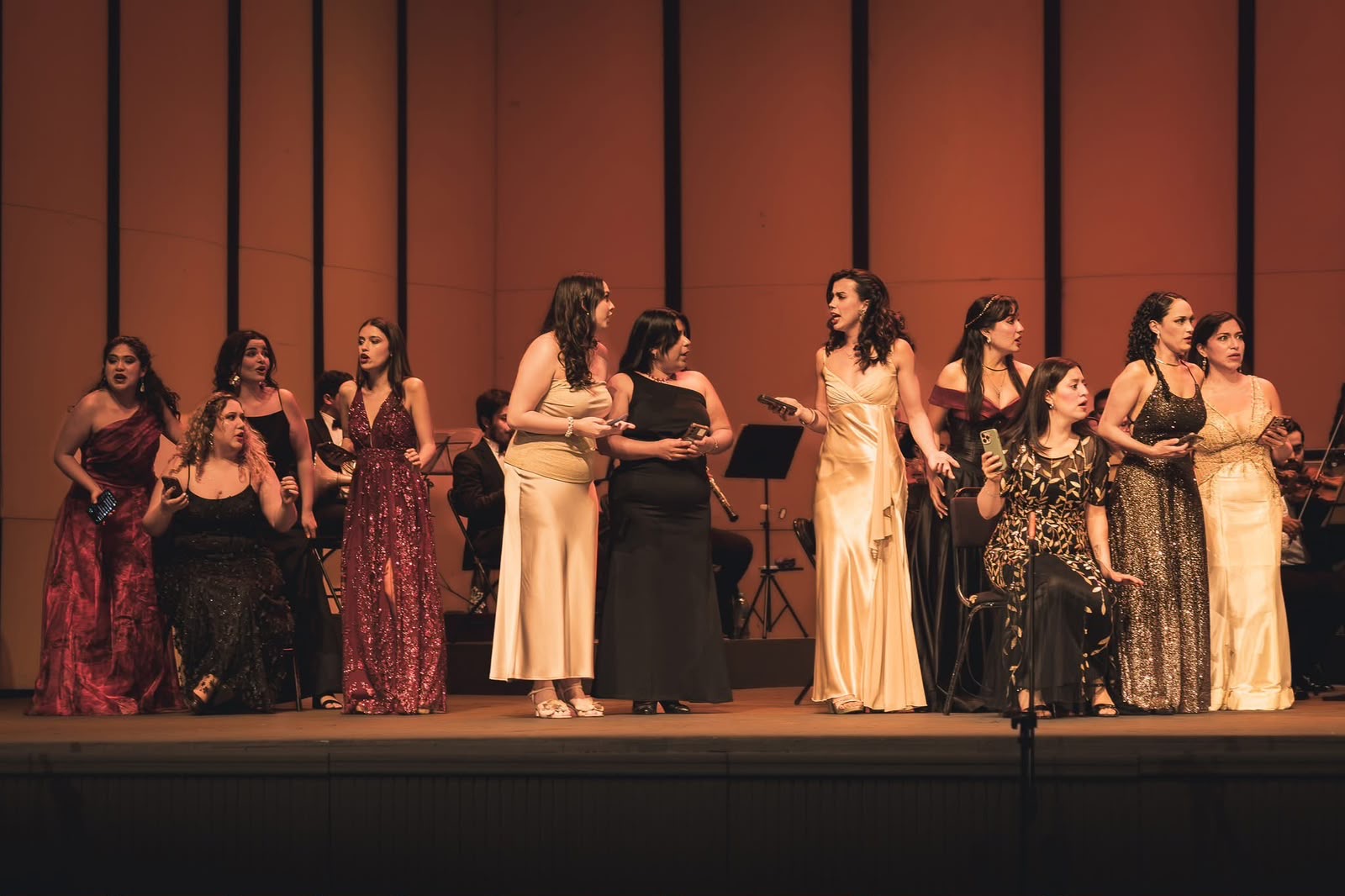 Elenco de ópera en escena acompañado por orquesta